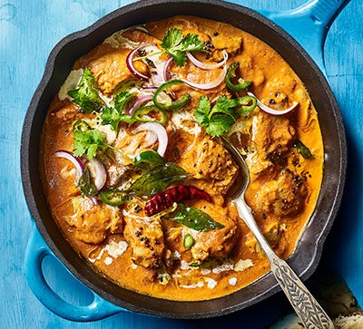 Butter chicken in pot with blue background