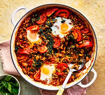 Spiced spinach eggs with tomatoes in a pot