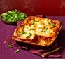 Chicken lasagne in a large baking dish, with torn salad leaves