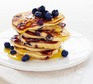 Blueberry pancakes with maple syrup stacked on a plate