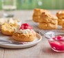 Rhubarb and custard scones on a plate with one scone sliced and spread with fresh cream and rhubarb compote