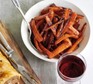 Roasted carrots in a bowl next to a glass of red wine