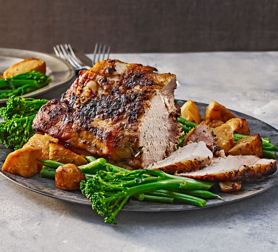 Slow cooker pork loin with roast potatoes and broccoli on a serving platter