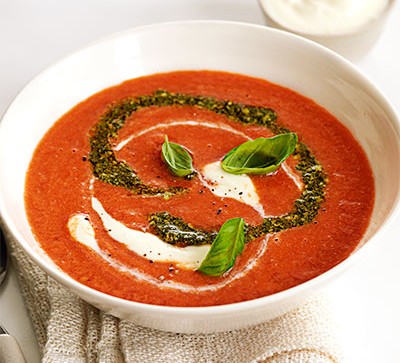 bowl of tomato soup with cream and pesto
