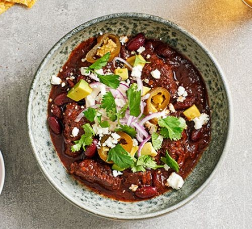 Chilli con carne topped with feta and salad in a bowl