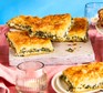 Cheese & spinach pie cut into squares on a board